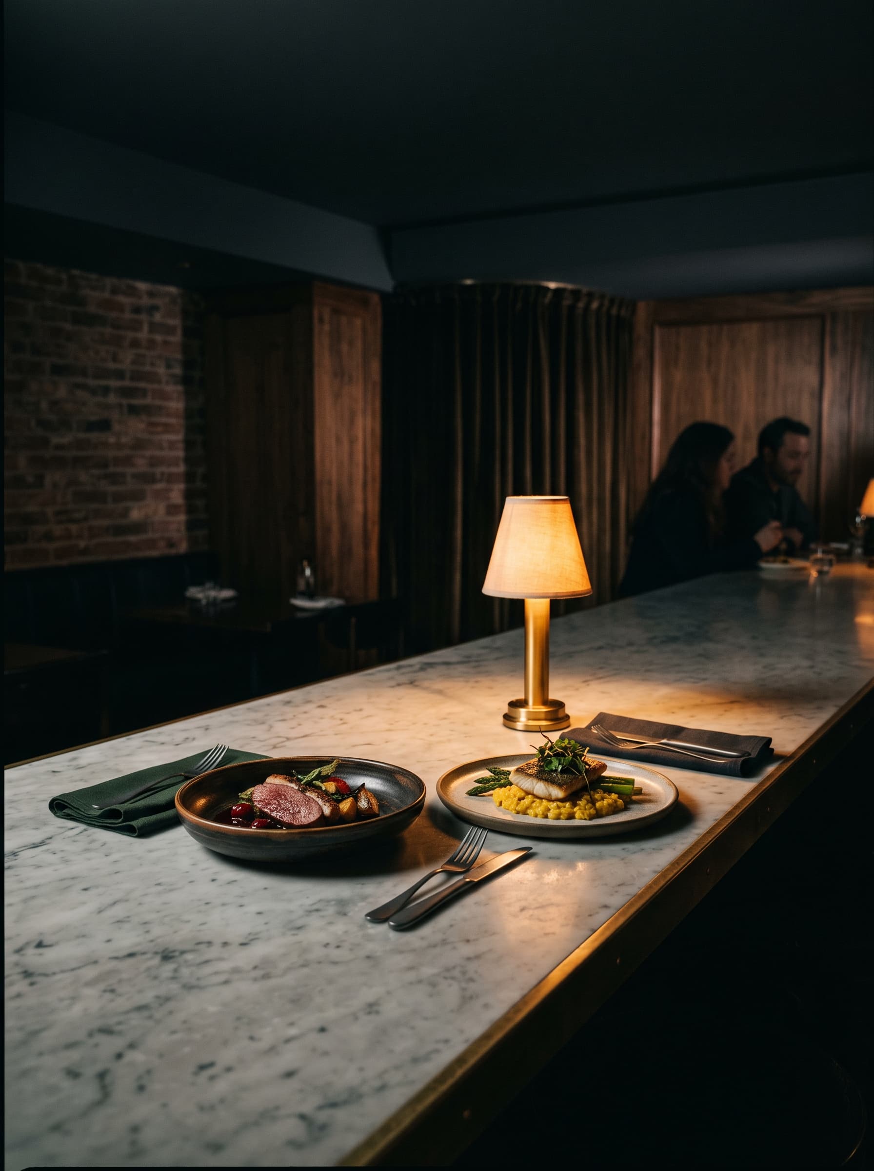 Two finished plates on the long marble counter beside a small brass lamp